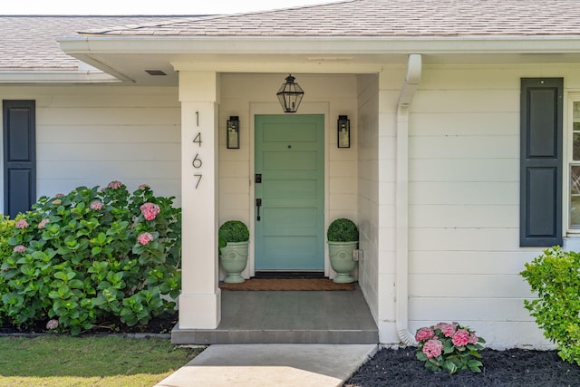view of exterior entry featuring roof with shingles