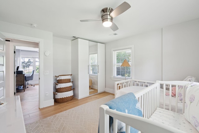 bedroom featuring multiple windows, a desk, light wood-type flooring, and a ceiling fan