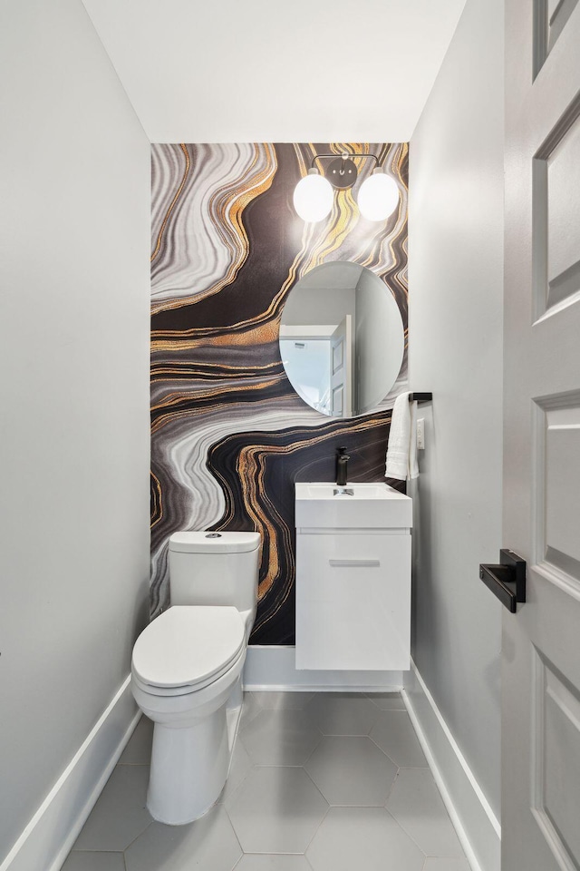 half bath featuring tile patterned flooring, toilet, baseboards, and vanity