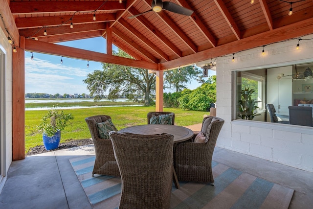 view of patio with a water view, a ceiling fan, and outdoor dining space