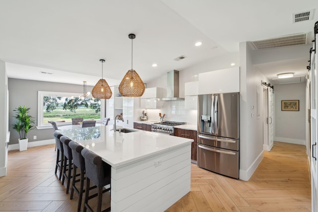 kitchen featuring stainless steel appliances, wall chimney exhaust hood, baseboards, white cabinetry, and modern cabinets