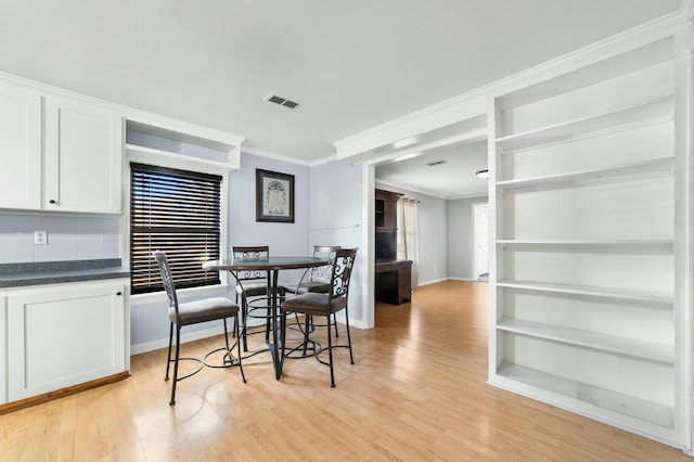 dining room with visible vents, baseboards, a wealth of natural light, light wood finished floors, and crown molding