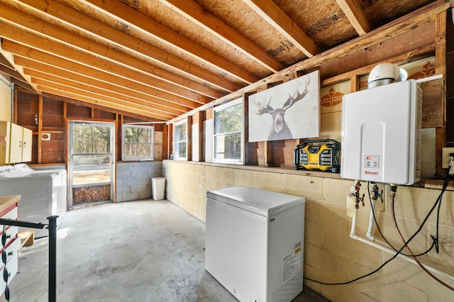 interior space featuring concrete block wall, tankless water heater, washer and dryer, and refrigerator