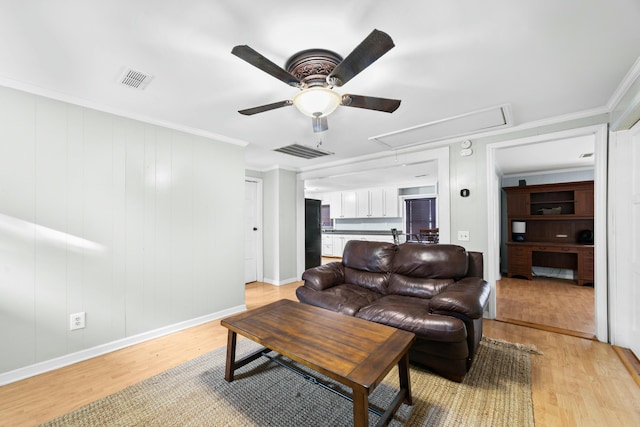 living area with light wood-type flooring, attic access, visible vents, and crown molding