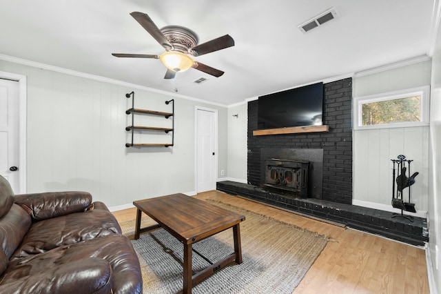 living area with ornamental molding, a fireplace, wood finished floors, and visible vents