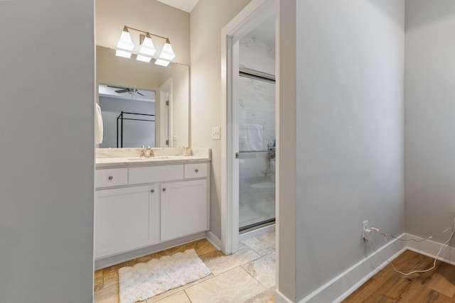 bathroom with a shower stall, vanity, a ceiling fan, and baseboards