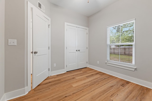 unfurnished bedroom featuring light wood-type flooring, baseboards, and a closet
