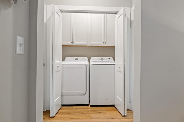 washroom featuring separate washer and dryer, cabinet space, and light wood-type flooring