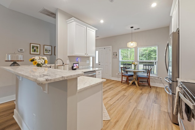 kitchen with appliances with stainless steel finishes, white cabinetry, light wood-style flooring, a peninsula, and recessed lighting