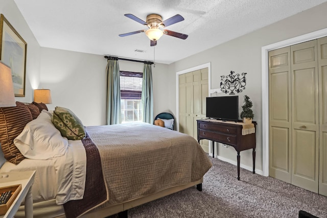 carpeted bedroom featuring two closets, a textured ceiling, and ceiling fan