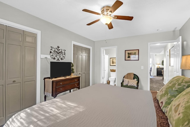 carpeted bedroom featuring connected bathroom, two closets, and ceiling fan