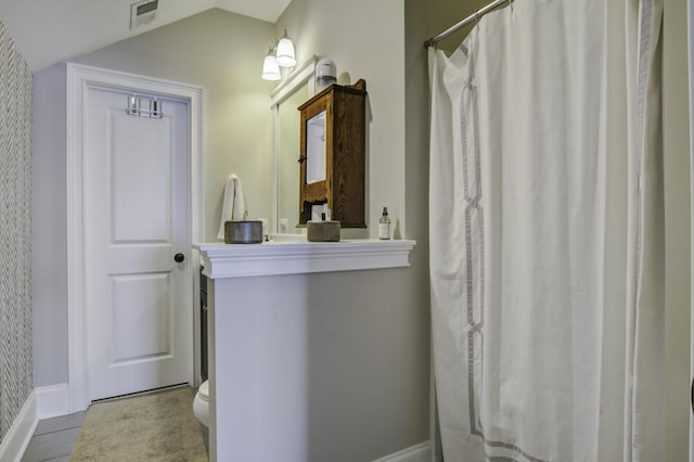 bathroom with vaulted ceiling, a shower with shower curtain, and toilet