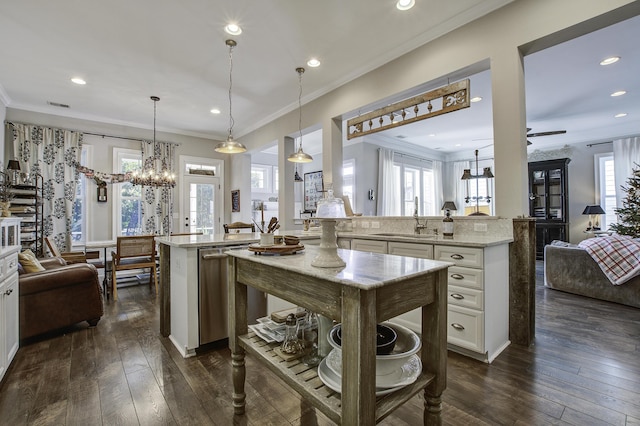 kitchen with sink, light stone countertops, decorative light fixtures, stainless steel dishwasher, and kitchen peninsula