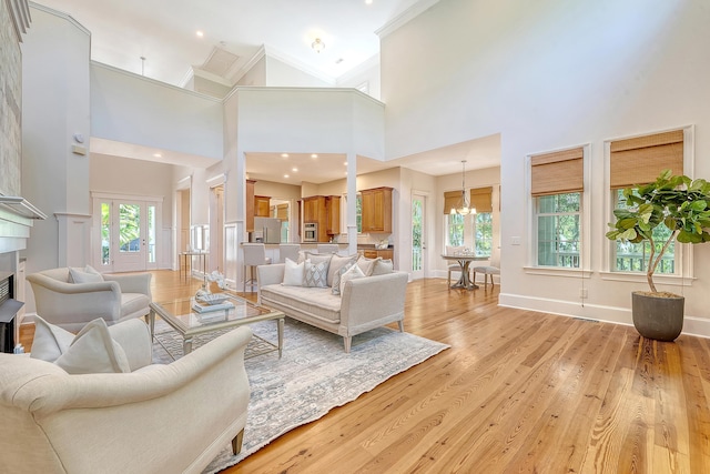 2701 Fountainhead Way, Mount Pleasant, SC 29466 - living room featuring a chandelier, a towering ceiling, plenty of natural light, light wood-style floors, and crown molding