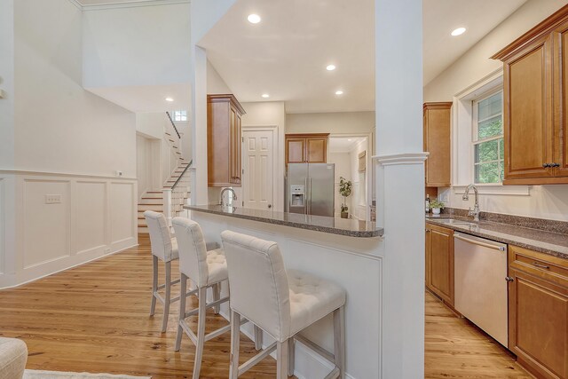 2701 Fountainhead Way, Mount Pleasant, SC 29466 - kitchen with stainless steel appliances, a sink, a breakfast bar, light wood finished floors, and brown cabinetry