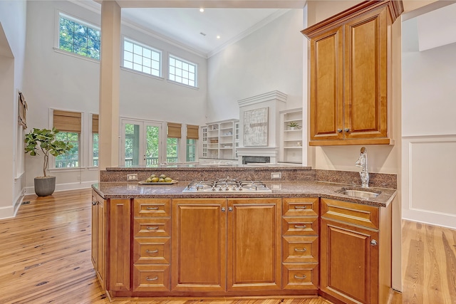 2701 Fountainhead Way, Mount Pleasant, SC 29466 - kitchen with gas cooktop, a towering ceiling, dark stone counters, brown cabinetry, and ornamental molding