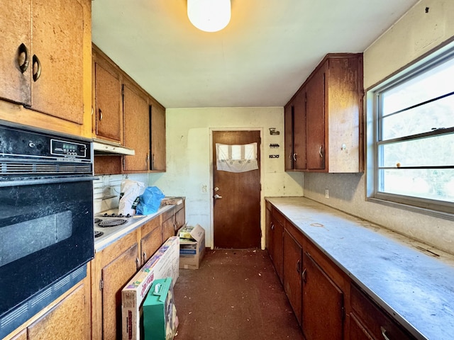 524 Kell Pl, Charleston, SC 29412 - kitchen with black oven, under cabinet range hood, light countertops, decorative backsplash, and brown cabinetry