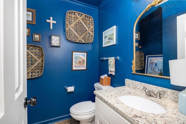 half bath with toilet, baseboards, crown molding, and vanity