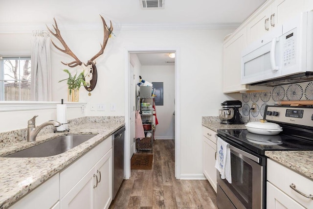 kitchen with crown molding, visible vents, appliances with stainless steel finishes, light wood-style floors, and a sink