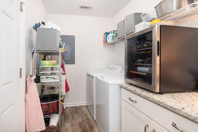 clothes washing area with laundry area, wood finished floors, visible vents, washer and dryer, and electric panel