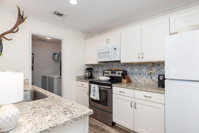 kitchen featuring white appliances, backsplash, washing machine and clothes dryer, and crown molding