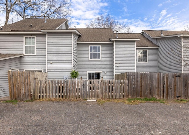 back of property featuring roof with shingles and fence