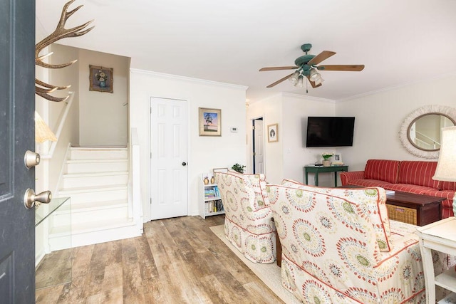 living room with ceiling fan, stairway, wood finished floors, and crown molding