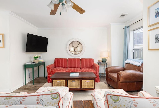 living area featuring baseboards, visible vents, a ceiling fan, ornamental molding, and wood finished floors