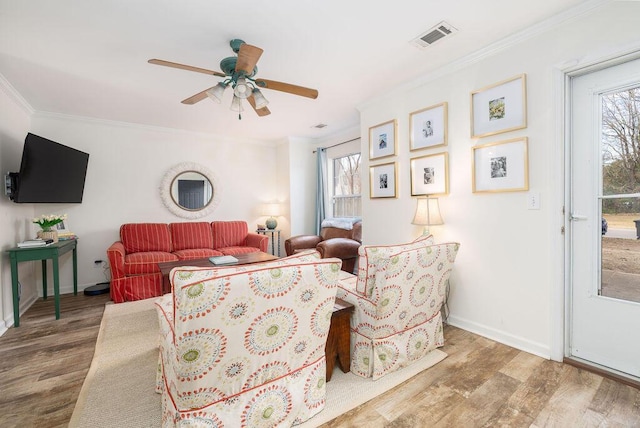 living area with visible vents, ornamental molding, a ceiling fan, wood finished floors, and baseboards