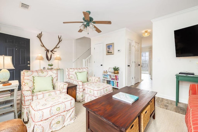 living area featuring baseboards, visible vents, ceiling fan, stairs, and crown molding