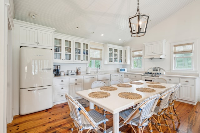 dining room with wood-type flooring, a notable chandelier, lofted ceiling, and sink