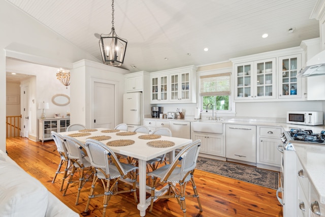 dining area with lofted ceiling, light hardwood / wood-style floors, sink, and a chandelier