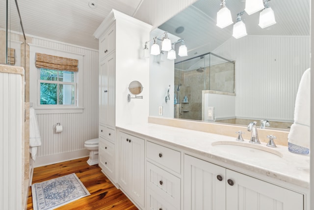 bathroom featuring vanity, wood walls, walk in shower, toilet, and hardwood / wood-style floors