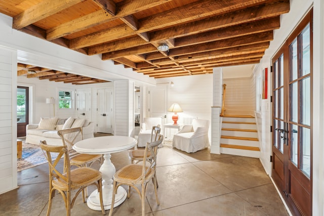 dining room with beam ceiling, concrete floors, and french doors