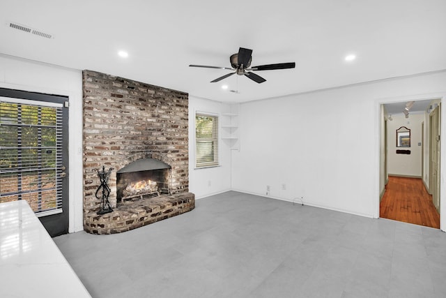 unfurnished living room with a brick fireplace, a wealth of natural light, and ceiling fan