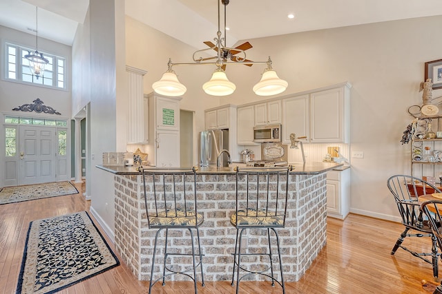 1308 Divot Ct, Mount Pleasant, SC 29466 - kitchen featuring high vaulted ceiling, stainless steel appliances, baseboards, light wood-style flooring, and a peninsula
