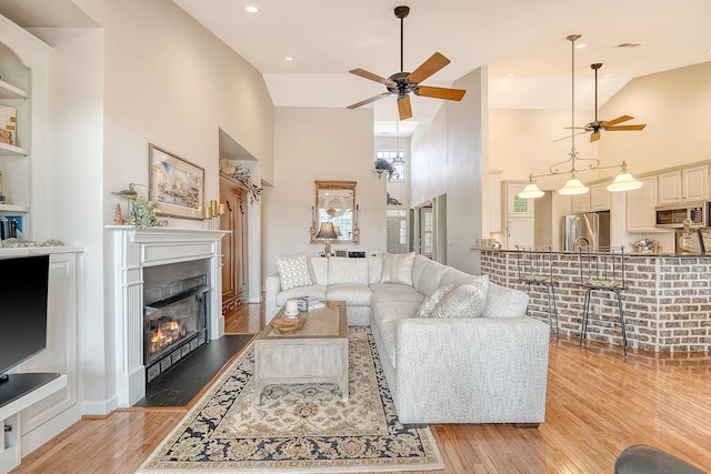 1308 Divot Ct, Mount Pleasant, SC 29466 - living room featuring a ceiling fan, light wood-style floors, a glass covered fireplace, and high vaulted ceiling