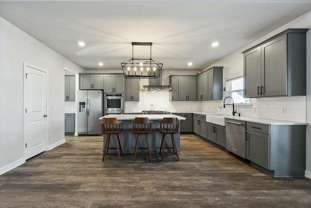 kitchen featuring stainless steel appliances, sink, dark hardwood / wood-style floors, a kitchen island, and hanging light fixtures