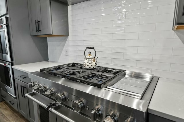 kitchen with decorative backsplash, appliances with stainless steel finishes, and gray cabinetry