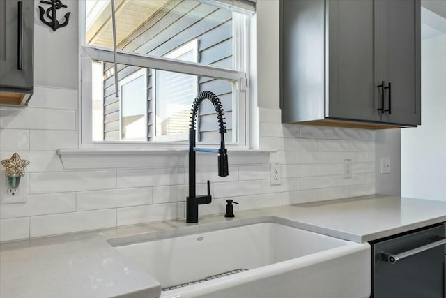 details with backsplash, stainless steel dishwasher, gray cabinetry, and sink