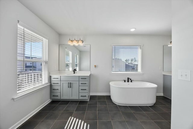 bathroom featuring tile patterned flooring, vanity, a bathtub, and a healthy amount of sunlight