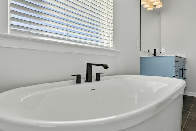 bathroom with a bathing tub, vanity, and tile patterned flooring