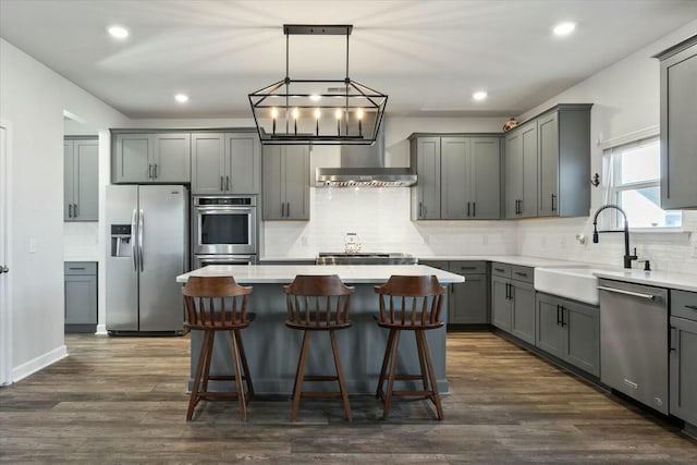 kitchen with gray cabinetry, sink, a center island, dark hardwood / wood-style floors, and appliances with stainless steel finishes