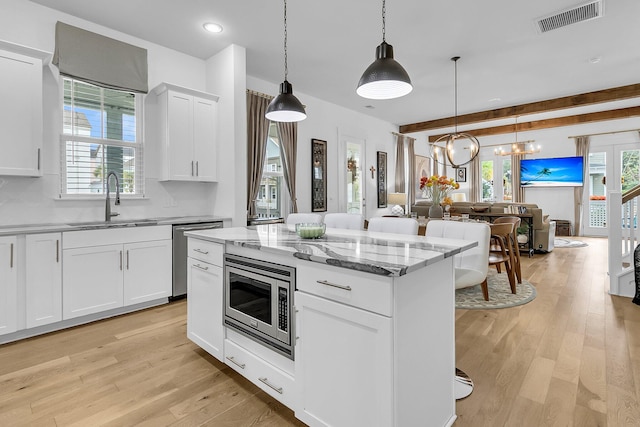 kitchen with a wealth of natural light, stainless steel appliances, light hardwood / wood-style flooring, and white cabinetry