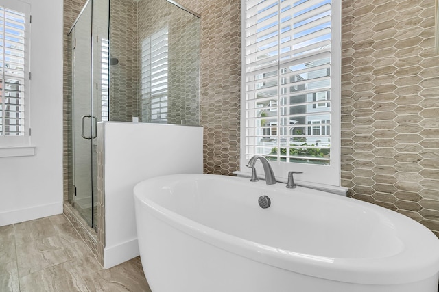 bathroom with shower with separate bathtub and plenty of natural light