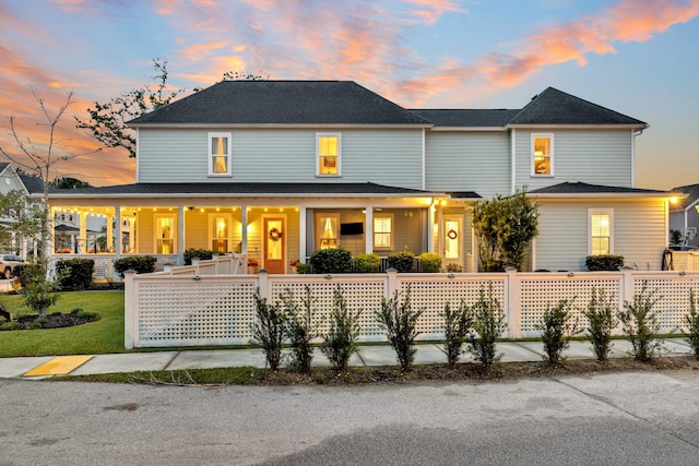 back house at dusk featuring a porch