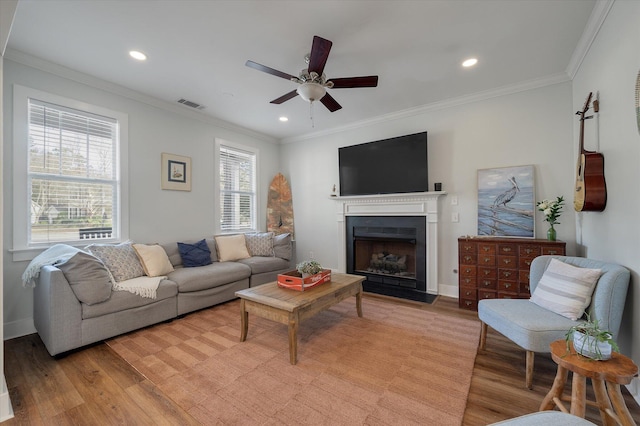 living room featuring crown molding, a healthy amount of sunlight, and light wood-type flooring