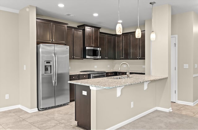 kitchen featuring sink, light stone counters, a kitchen breakfast bar, pendant lighting, and stainless steel appliances