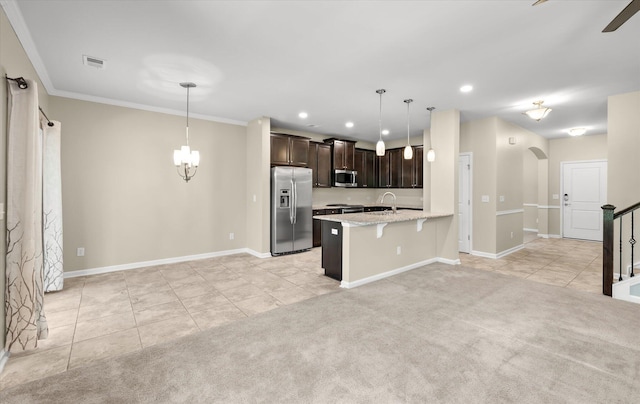 kitchen with appliances with stainless steel finishes, a breakfast bar area, light colored carpet, and decorative light fixtures