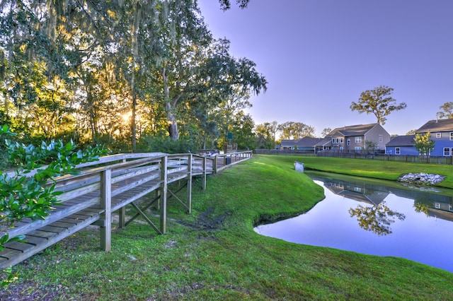 yard at dusk featuring a water view